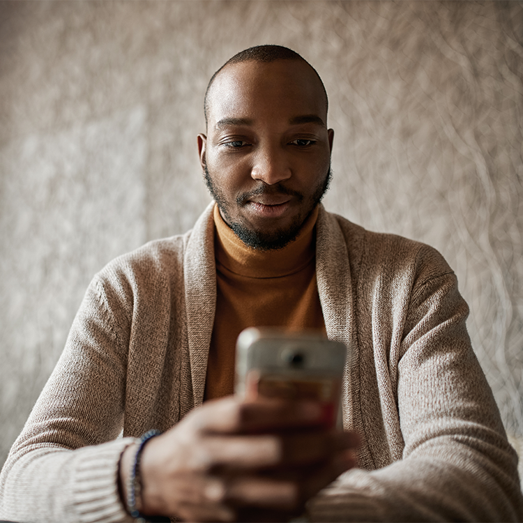 Black african business man looking down reading texts on mobile phone.